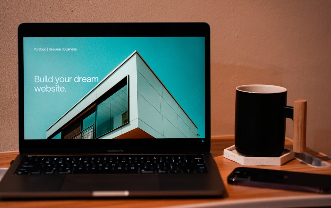 Créez le site web de vos rêves pour l’avenir. Un ordinateur portable, MacBook, posé sur une table pliante avec une tasse de café ou de thé à côté.